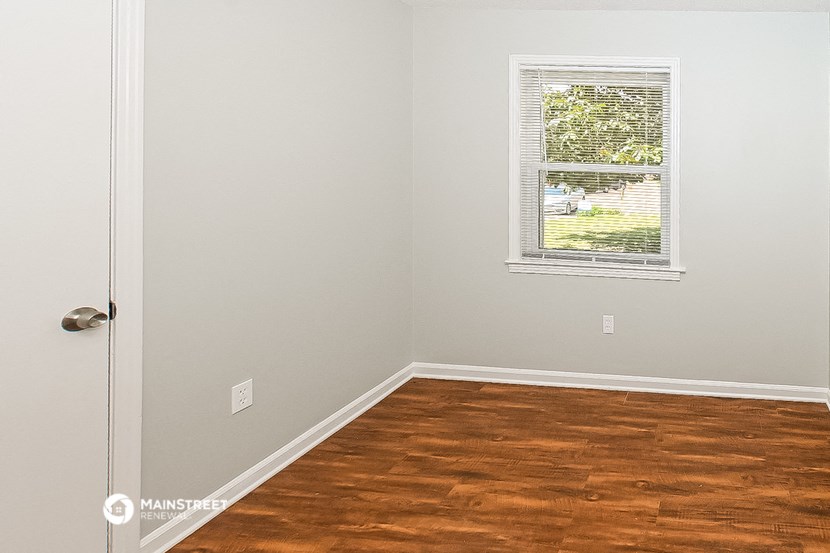 an empty room with wood floors and a window