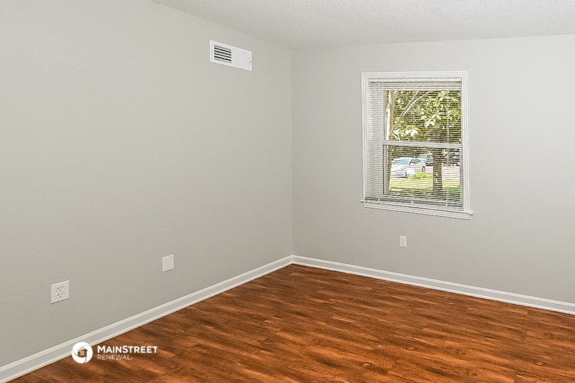 an empty room with wood floors and a window