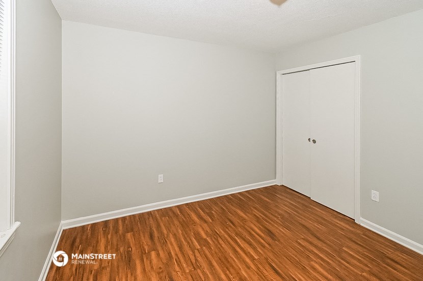 a bedroom with wood flooring and a white door