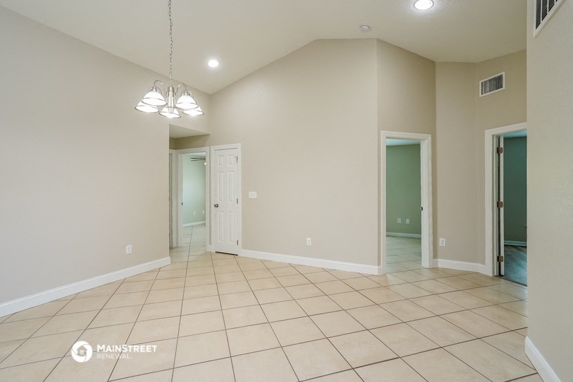 the spacious living room with tile flooring and a door to the hallway