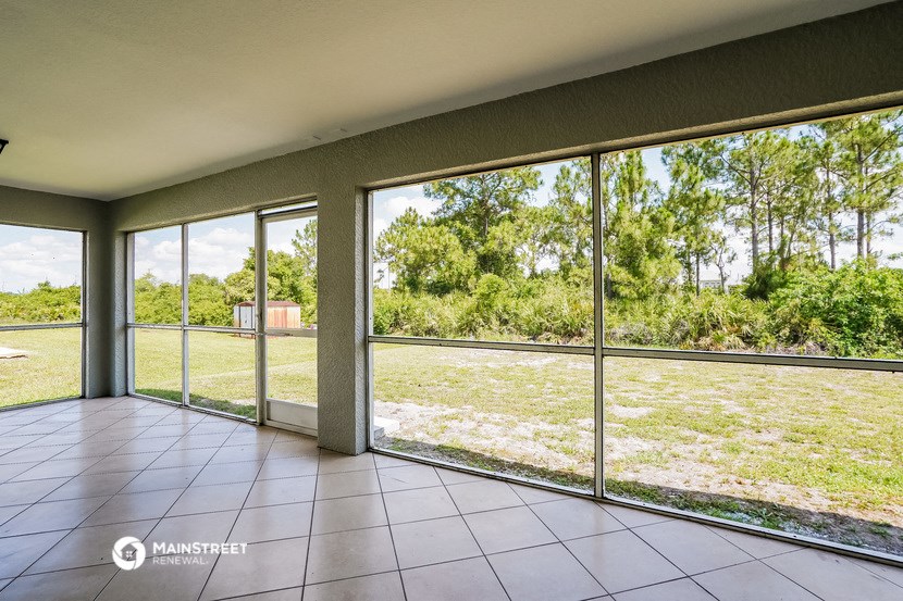 a view of the yard from the inside of a house with large windows