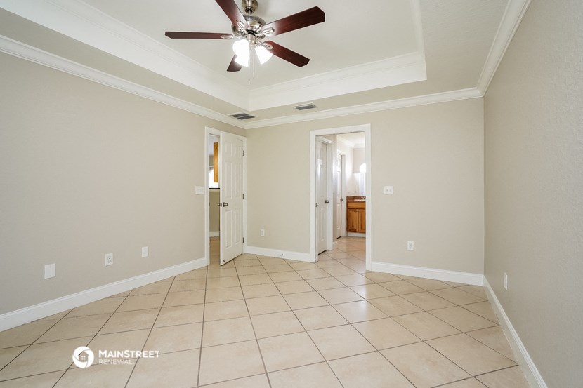 an empty living room with a ceiling fan and tiled floor