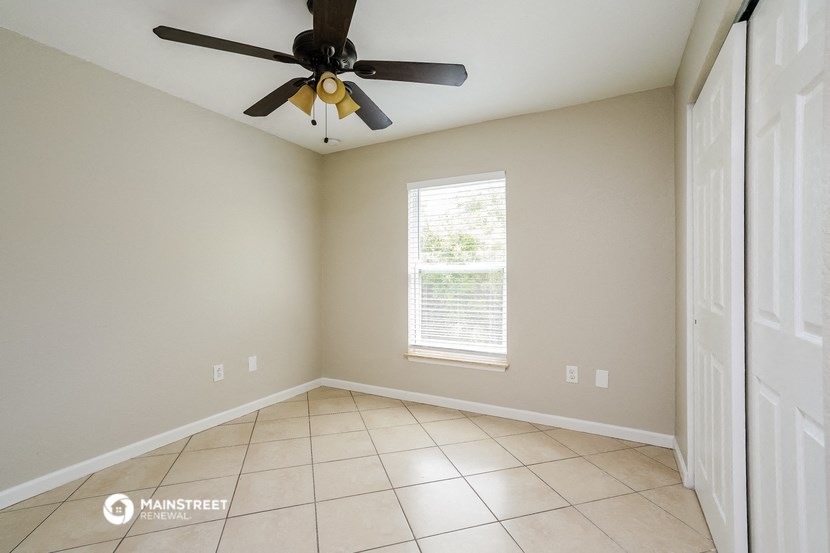 an empty living room with a ceiling fan and tiled floors