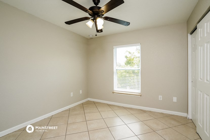 an empty living room with a ceiling fan and a window