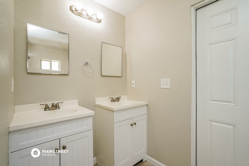 a white bathroom with two sinks and a mirror