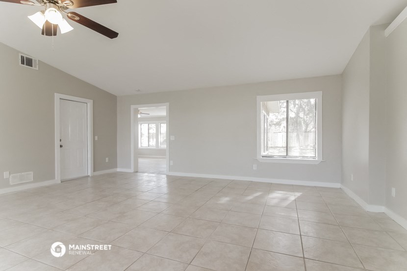 the spacious living room with tile flooring and a ceiling fan