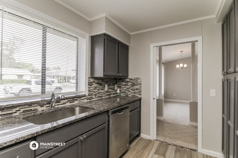 the kitchen of a home with a large window and a sink
