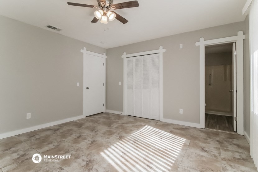 an empty living room with a ceiling fan and a closet