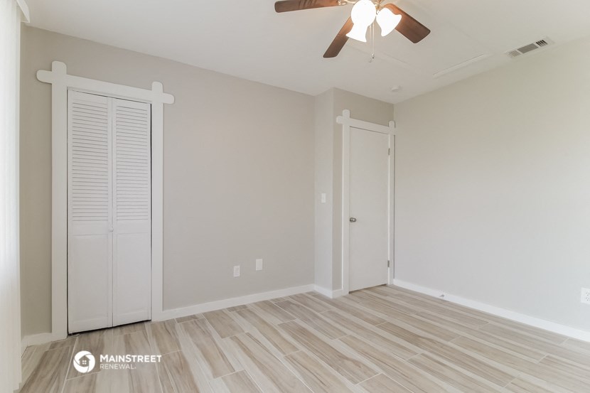 a bedroom with a ceiling fan and a closet