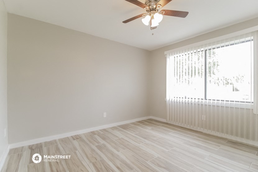an empty room with a ceiling fan and a window
