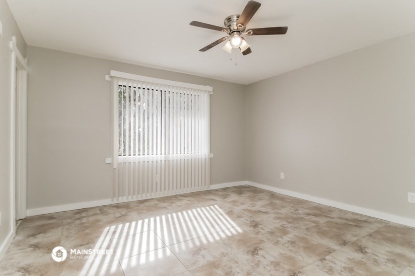 an empty living room with a ceiling fan and a window