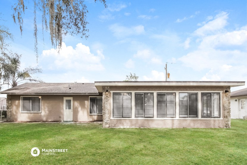 the front of a house with a grassy yard and a cloudy sky