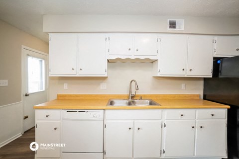a kitchen with white cabinets and a wooden counter top