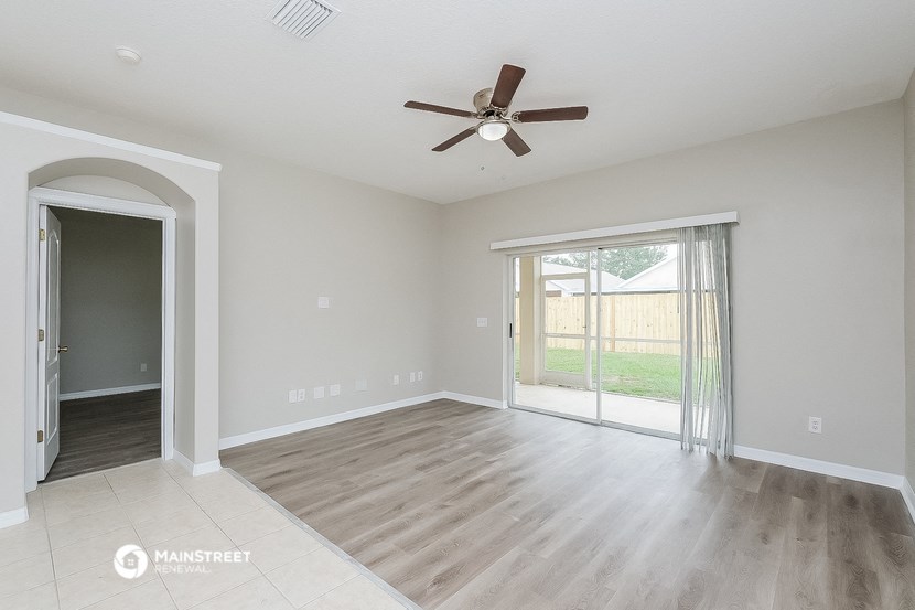 an empty living room with a ceiling fan and a sliding glass door