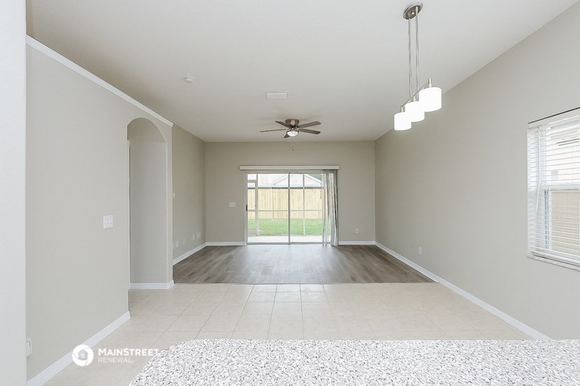 an empty living room with a ceiling fan and a window