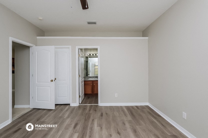 a living room with white walls and a door to a bathroom