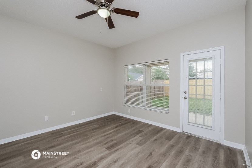 the spacious living room of a manufactured home with a ceiling fan and a door to