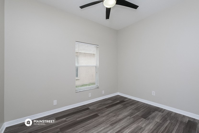 the interior of a room with wood flooring and a ceiling fan
