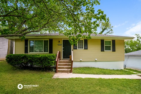 a yellow house with a tree in front of it