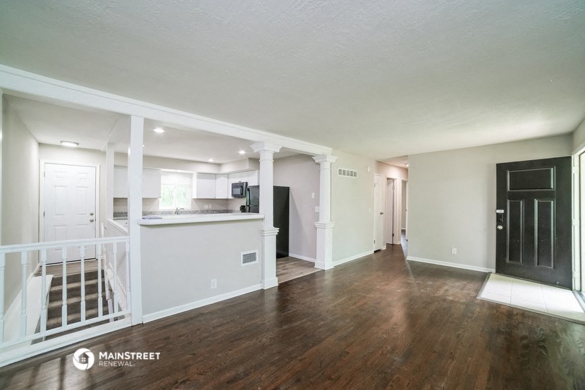 the living room and kitchen of a renovated house with wood flooring and a staircase