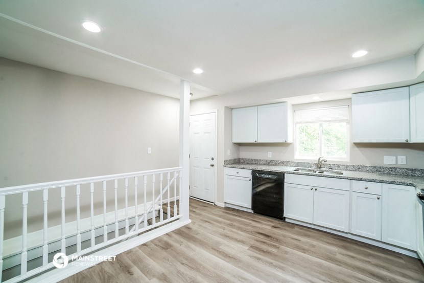 a white kitchen with white cabinets and a black dishwasher