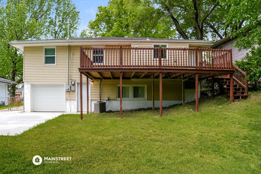 the back of a yellow house with a deck and a porch