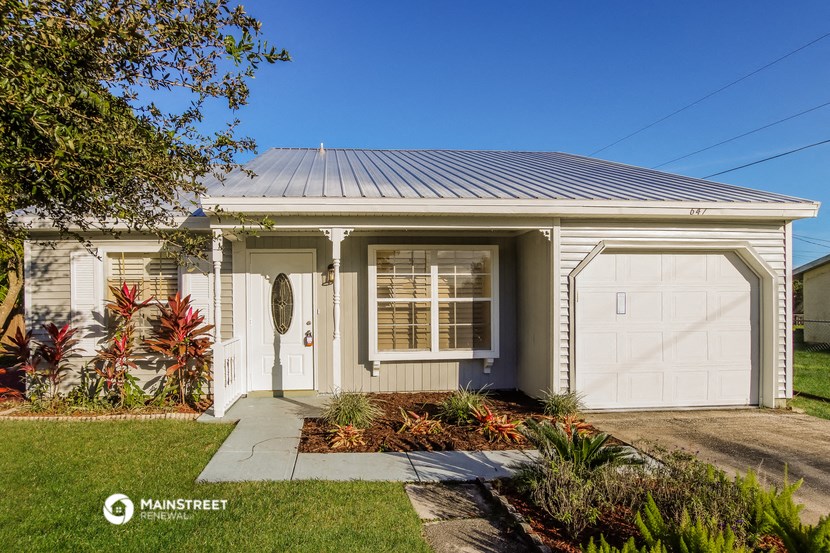 a small white house with two garage doors and a driveway