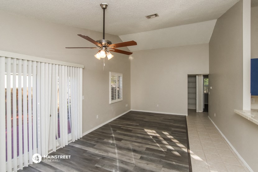 an empty living room with a ceiling fan and a window
