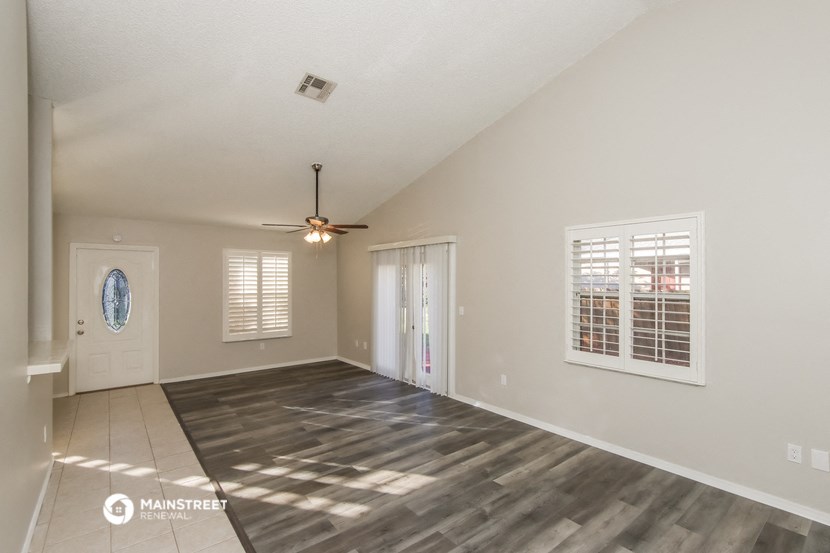 the living room is spacious and has a ceiling fan