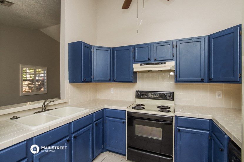 a kitchen with blue cabinets and a stove and sink