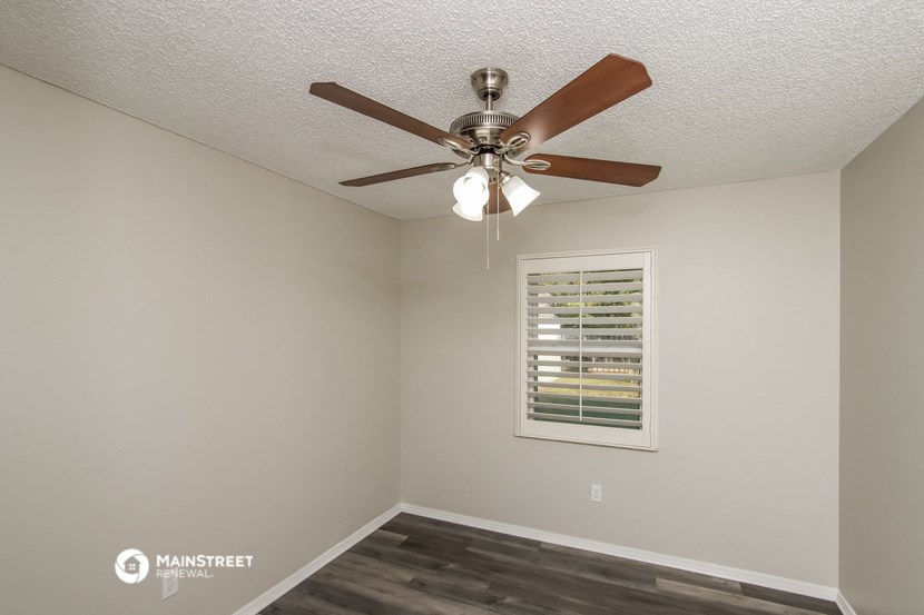 the interior of a bedroom with a ceiling fan and a window