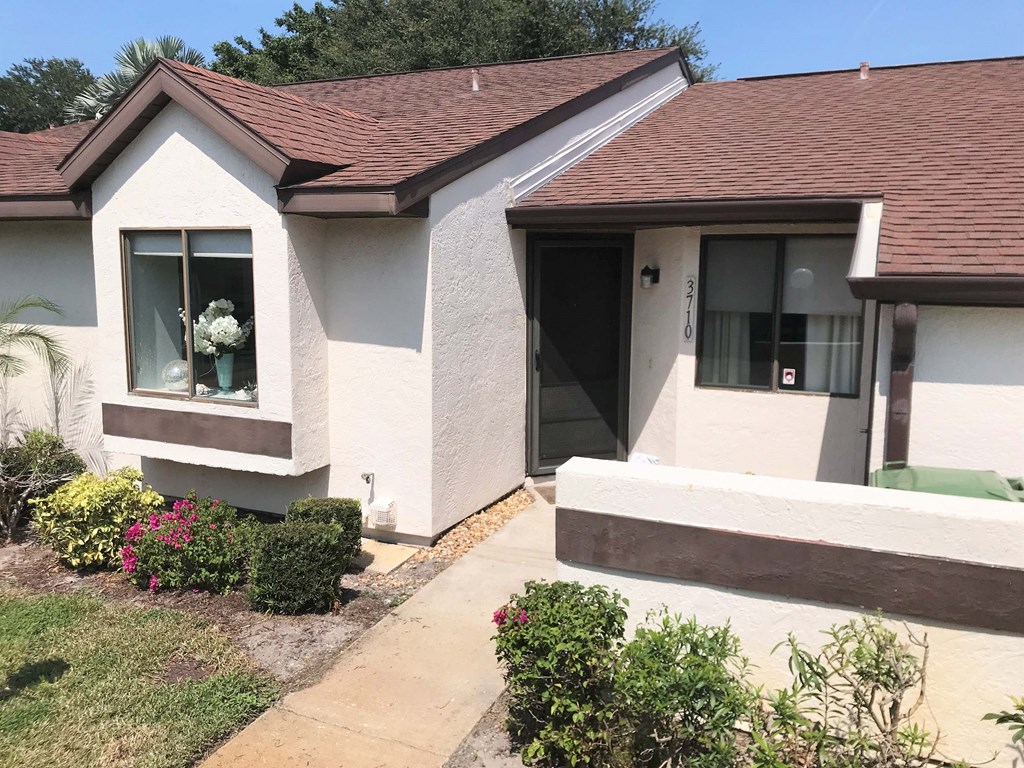 A house with a brown roof and a white wall with a window and a door.