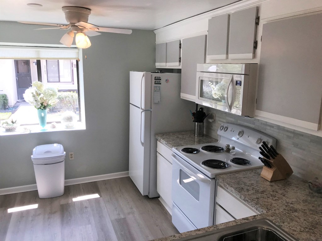 A kitchen with a white refrigerator, stove, and cabinets.