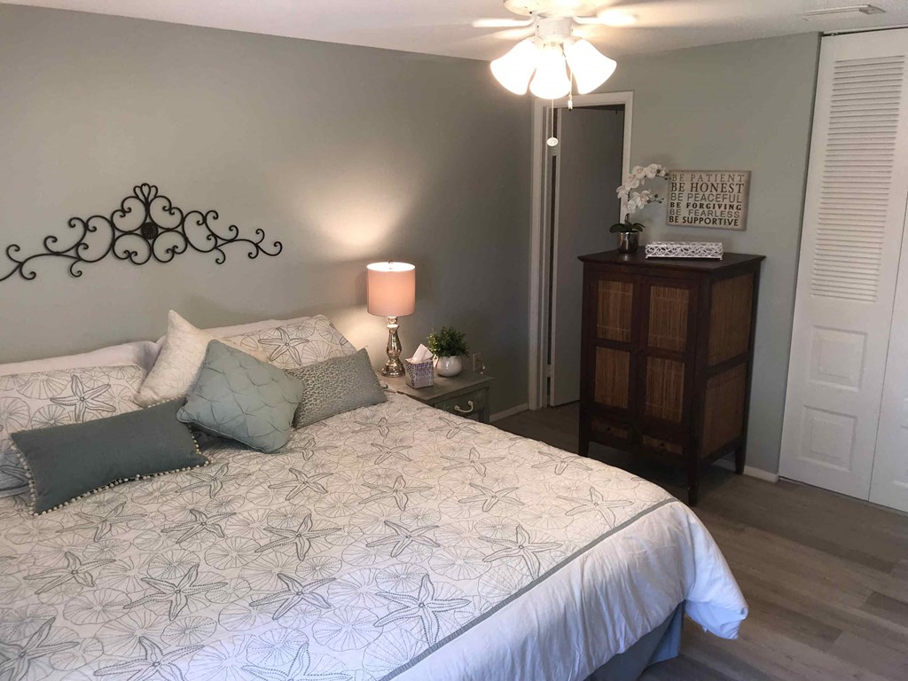 A bedroom with a bed, a lamp, and a decorative headboard.