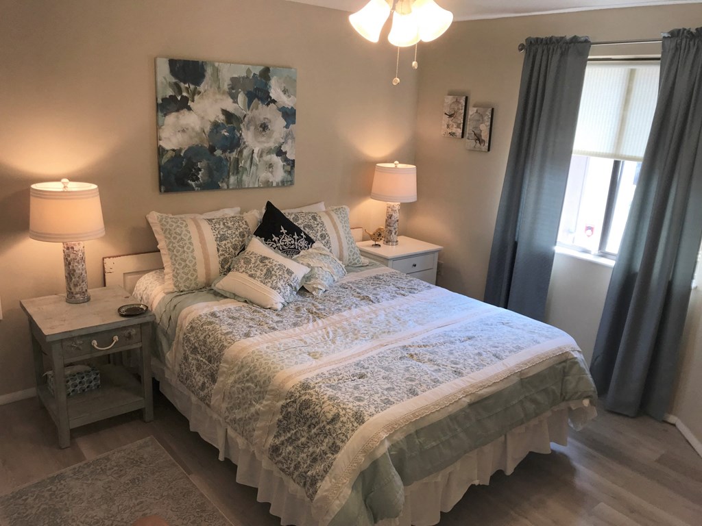 A bedroom with a bed, nightstands, and a painting on the wall.