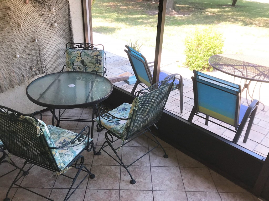 A glass table and chairs are on a patio.