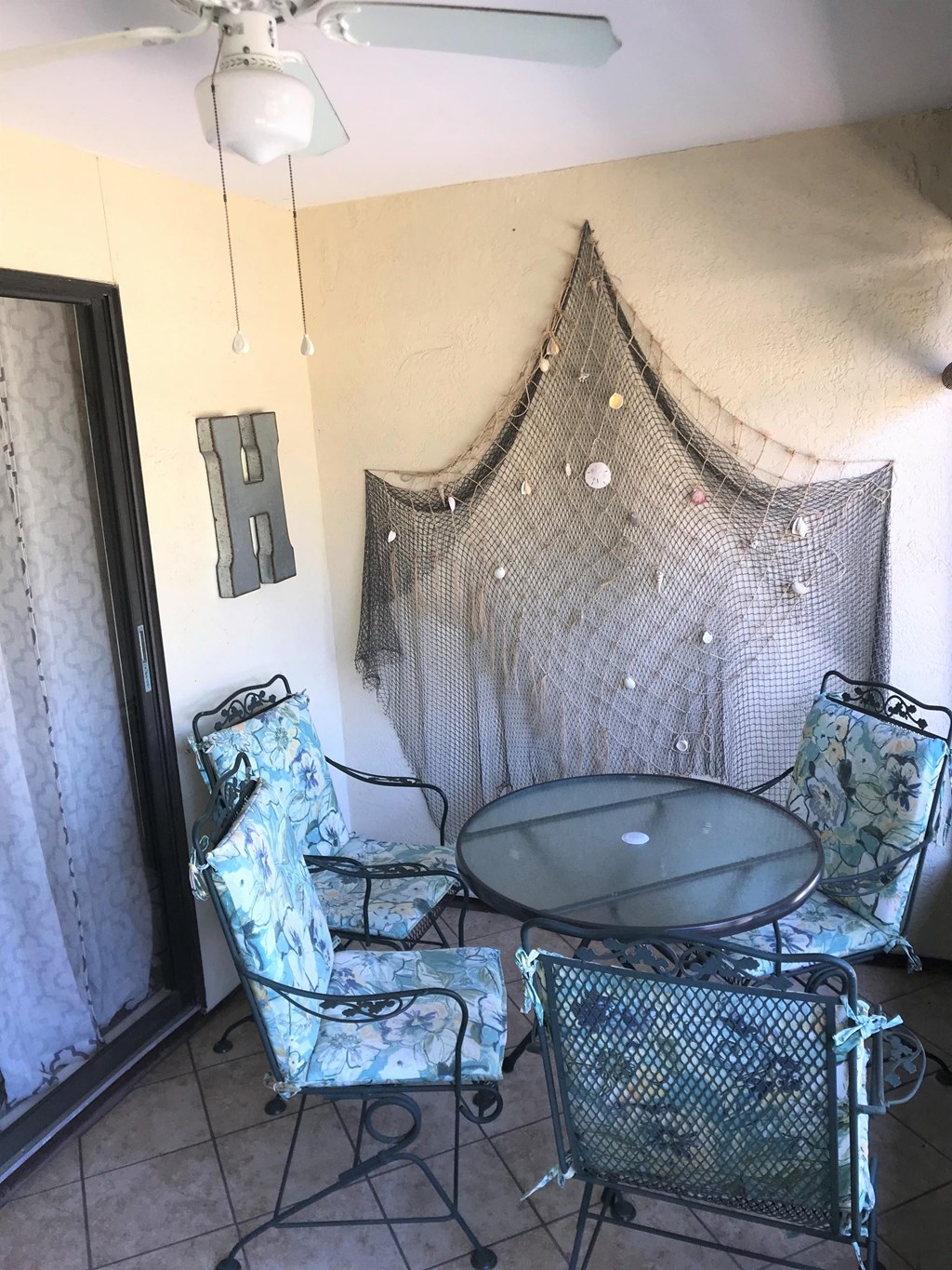 A patio with a table, two chairs, and a mosquito net.