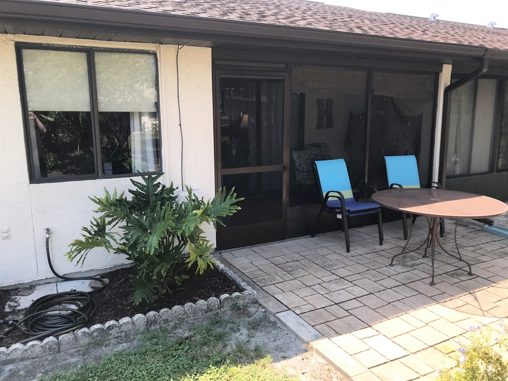 A patio with a table and chairs outside a house.