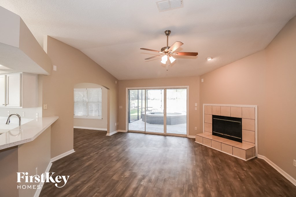 an empty living room with a fireplace and a ceiling fan