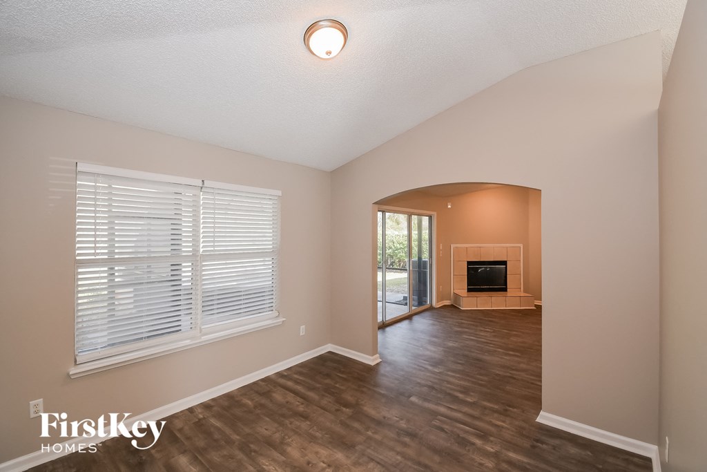 the living room and dining room of an empty house with a fireplace