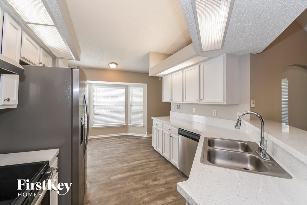 a kitchen with white cabinets and a stainless steel sink and refrigerator