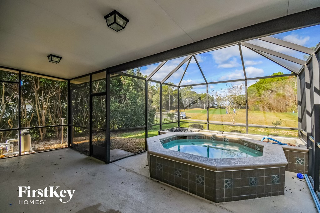 a hot tub in a conservatory with glass doors and a view of the backyard