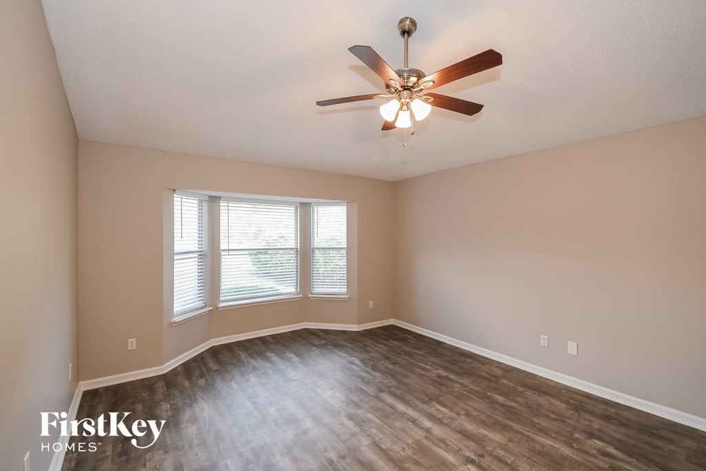 an empty living room with a ceiling fan and a window