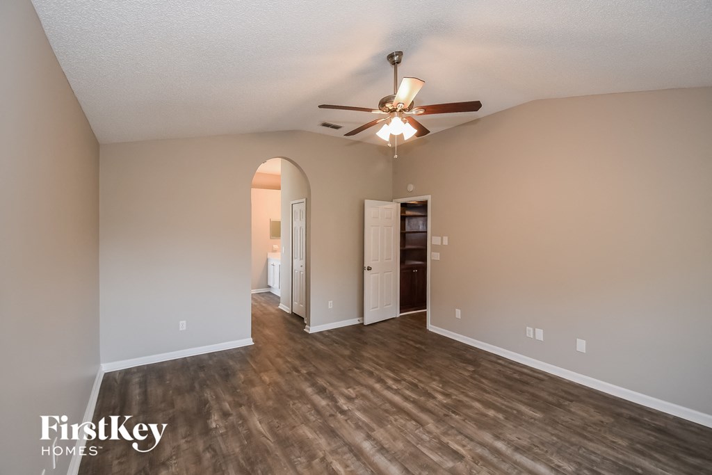 a living room with a ceiling fan and a door into a hallway