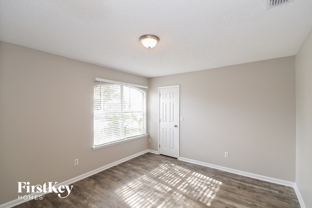 the spacious living room with a large window and wood flooring