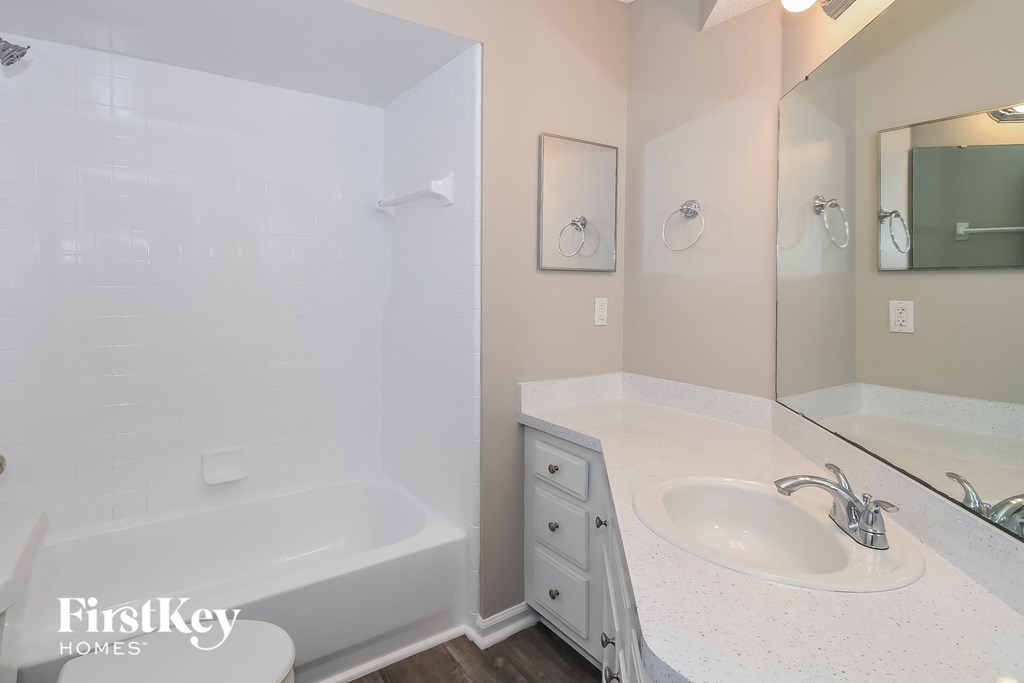 a white bathroom with a tub and sink and a mirror