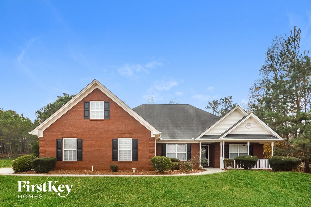 a red brick house with a gray roof and green grass