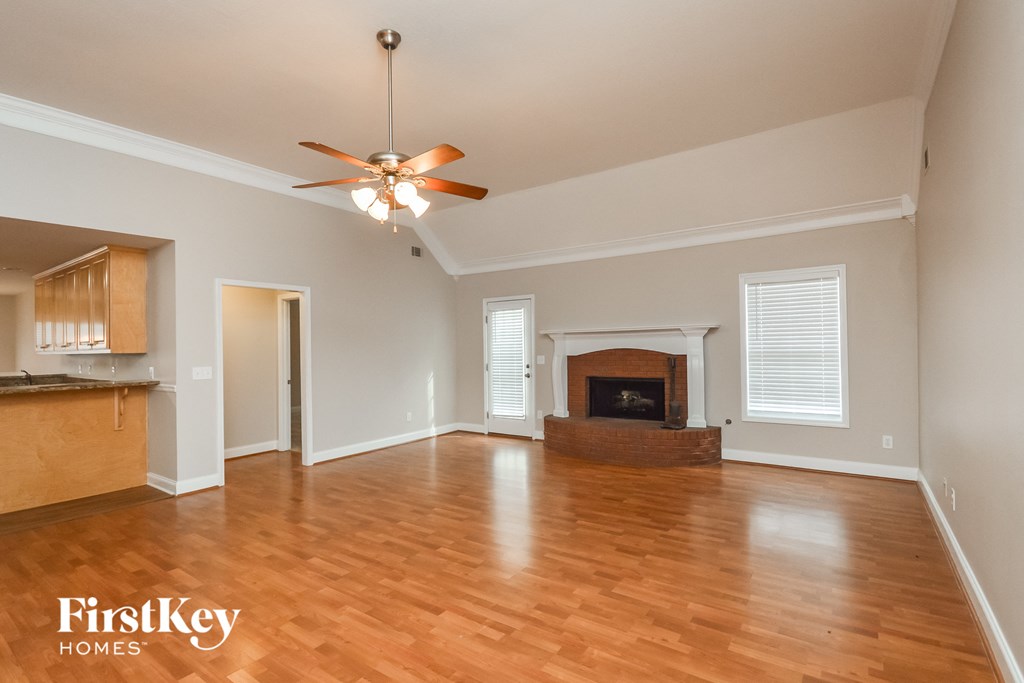an empty living room with a fireplace and a ceiling fan