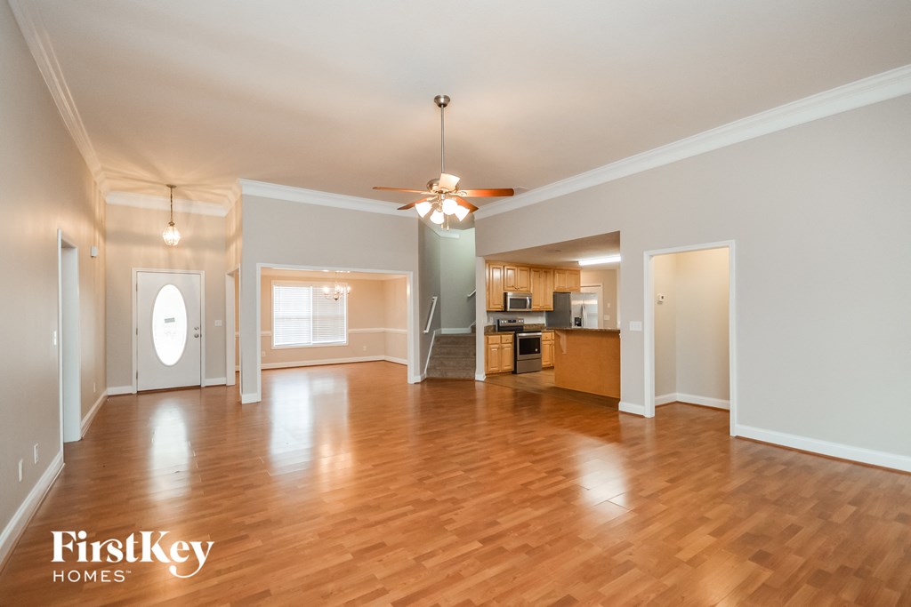 an empty living room and kitchen with wood flooring and a ceiling fan