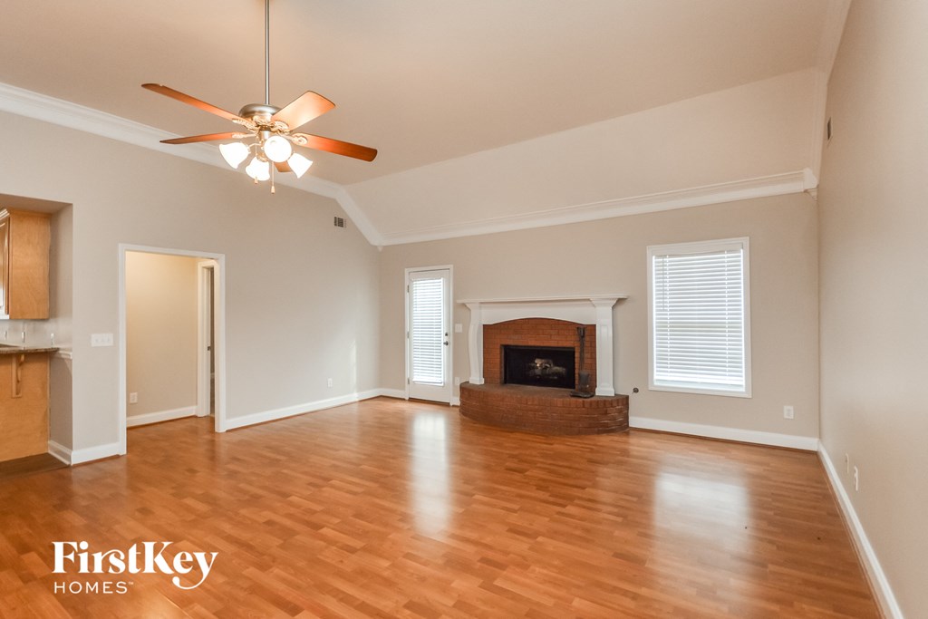 an empty living room with a fireplace and a ceiling fan